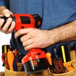 man holding a drill and wearing a toolbelt